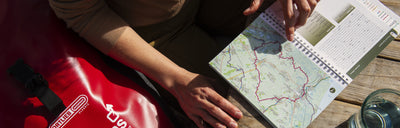 Woman is reading cycling guidebook at a picnic bench