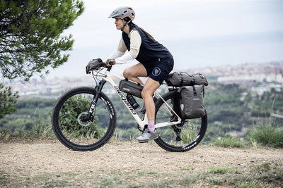 Person riding a bicycle with gear on a scenic trail