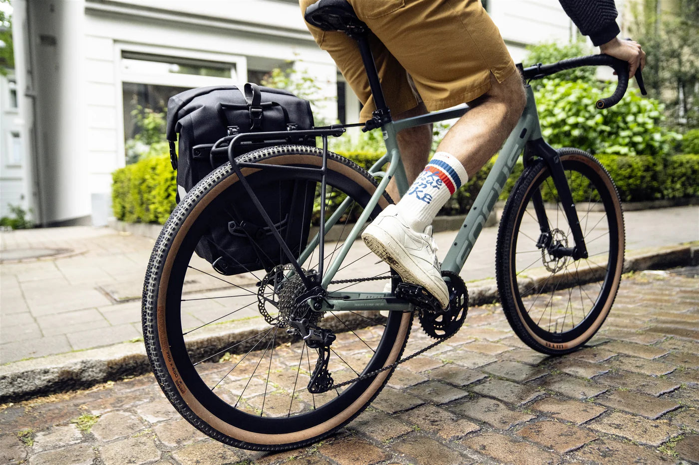 Person riding a bicycle with quick-rack on bike. Pannier on bike. 