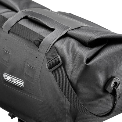 Black Ortlieb trunk bag with visible branding on a white background. Showing the shoulder strap. 